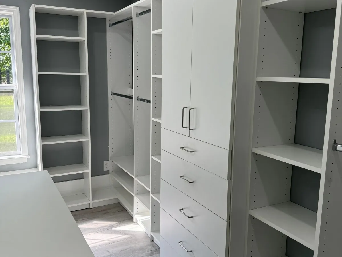 Freshly installed white custom reach-in closet with drawers and matte black hardware
